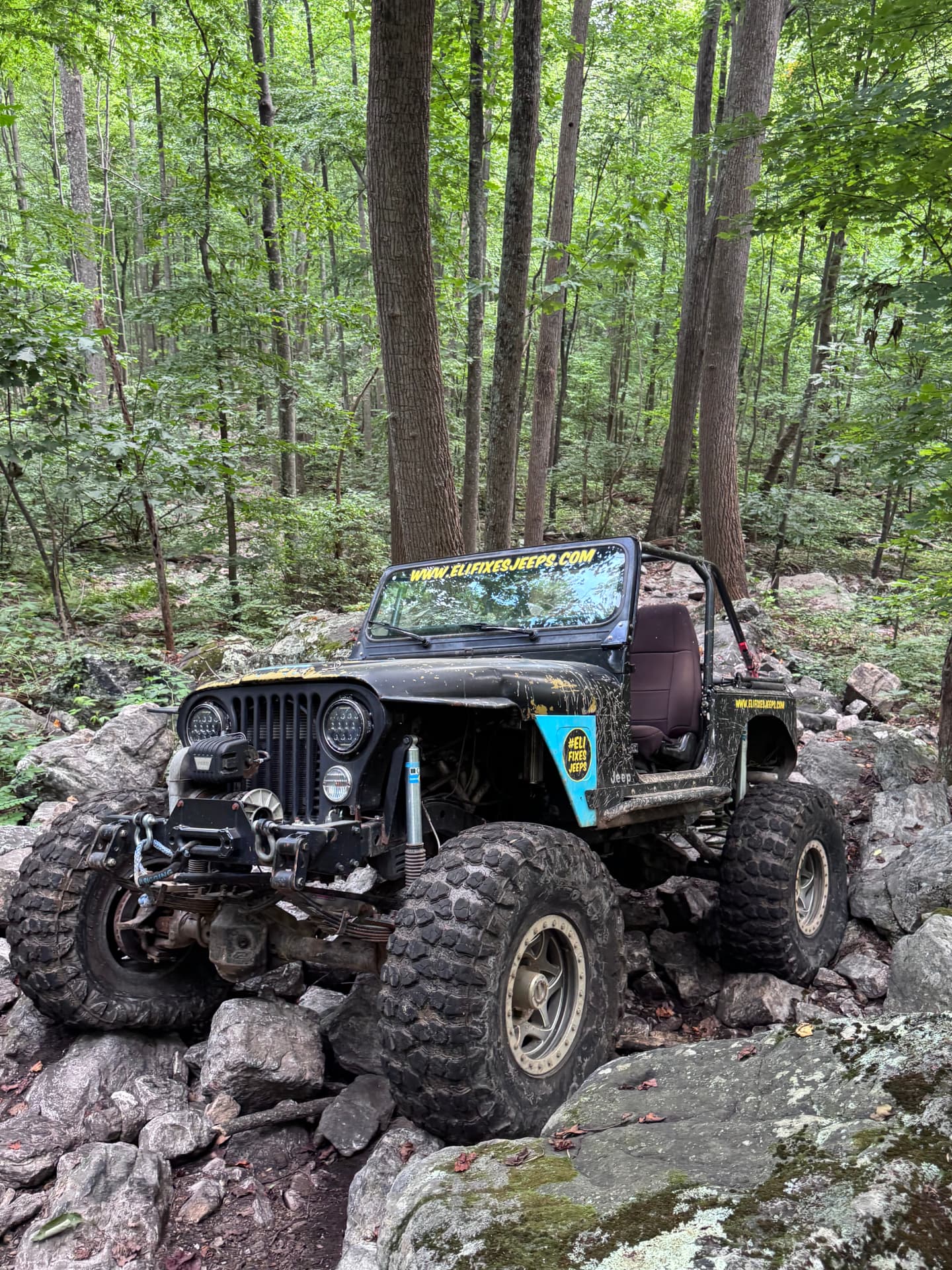 Judy, EFJ’s custom 1979 CJ7 shop Jeep, navigating a rocky wooded trail.